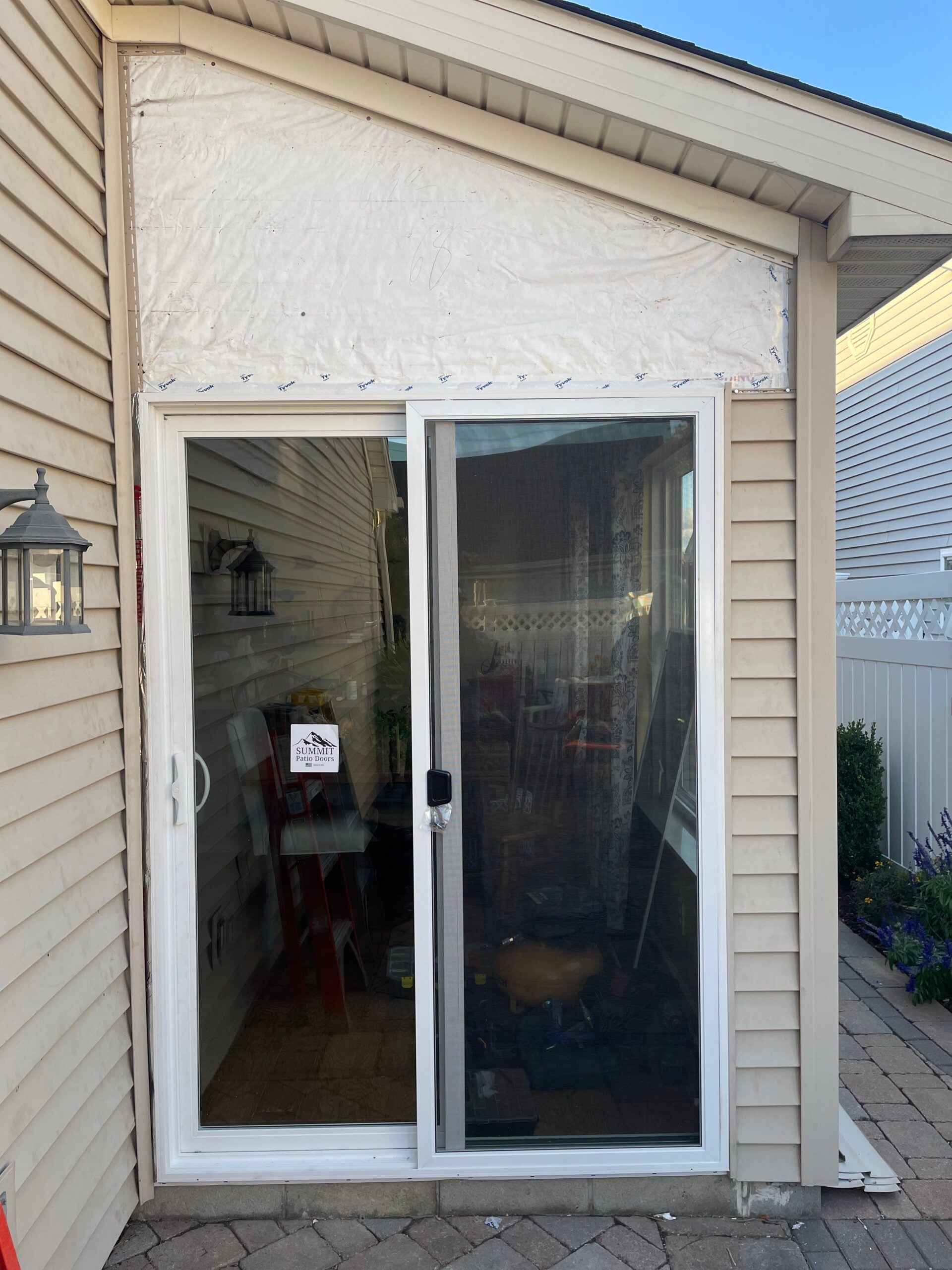 New sliding patio door installation with exterior weatherproofing prepared for finishing and siding work.