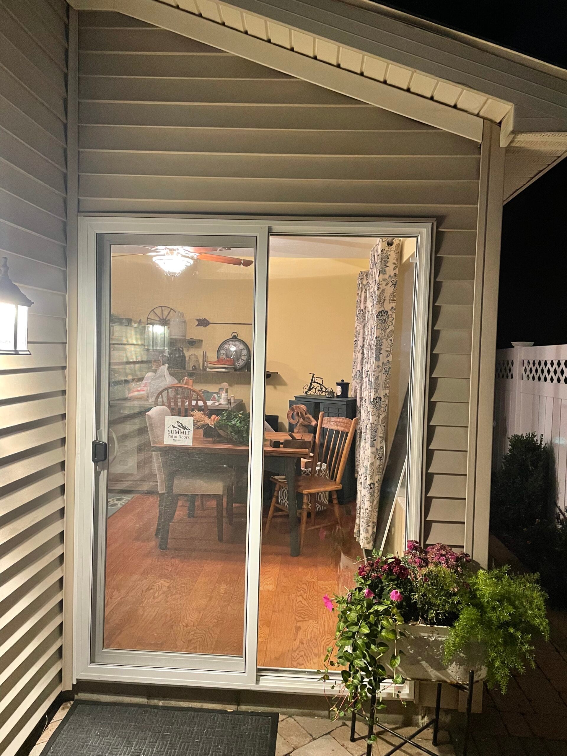 New white sliding patio door installed beneath finished vinyl siding and exterior trim.