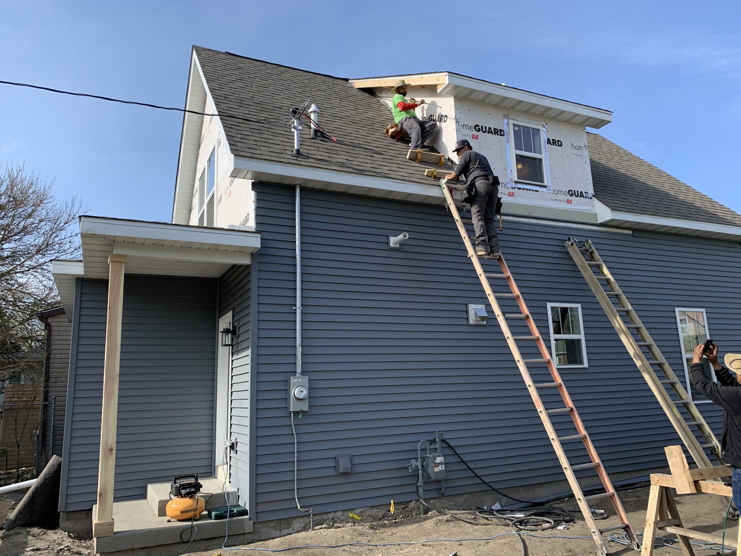 Contractors installing siding and exterior finishes on a two-story home addition during remodeling.