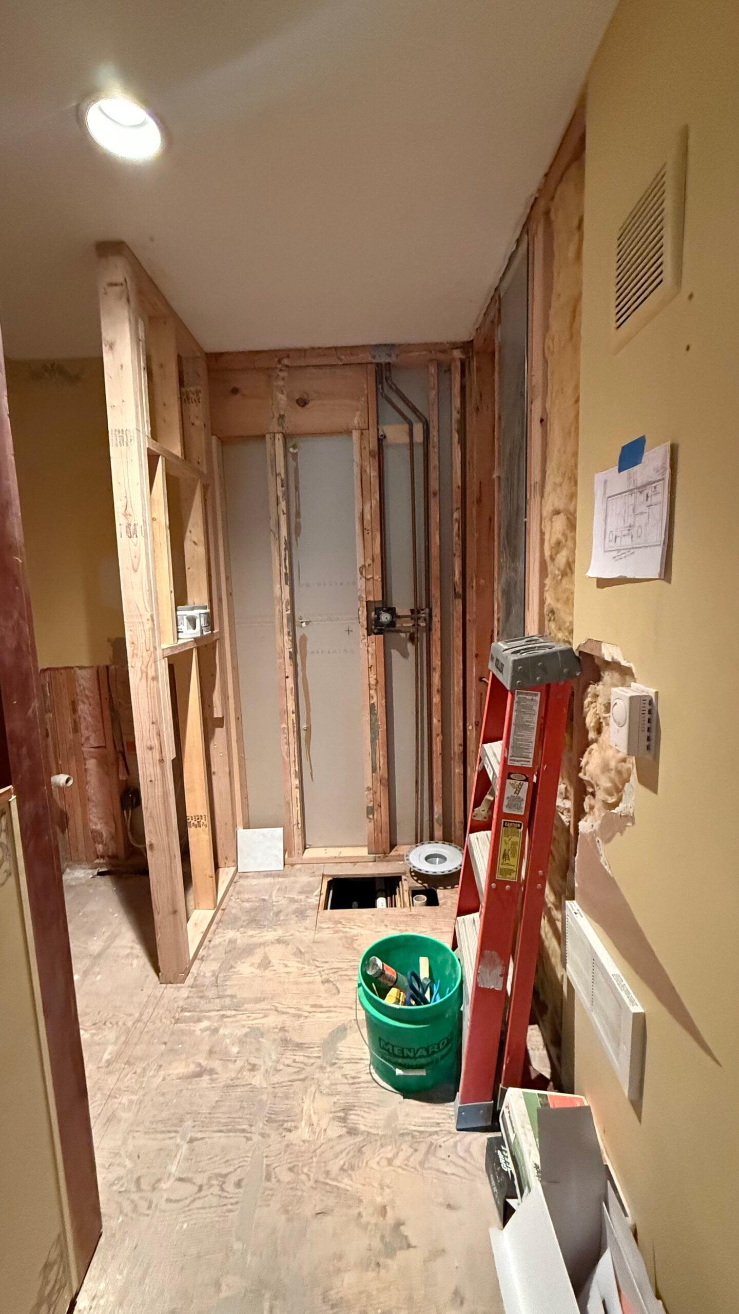 Bathroom renovation in progress with walls opened for new framing, plumbing, electrical work, and layout improvements.